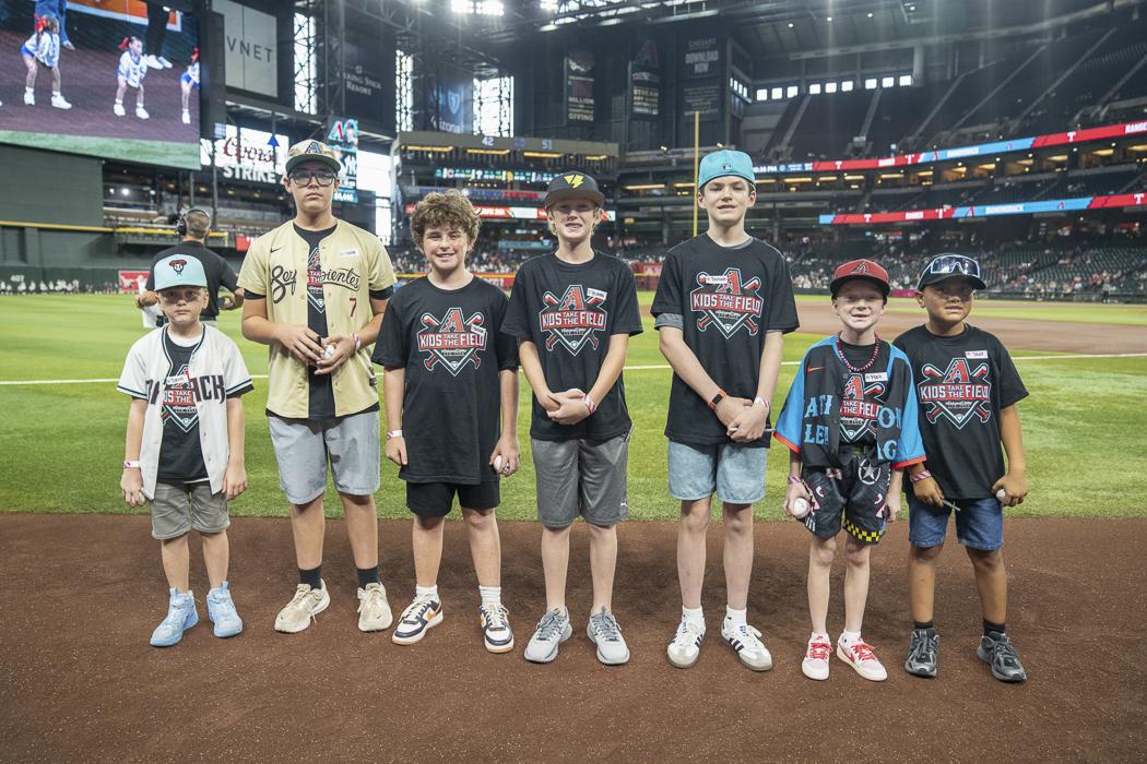 Seven Kids Take the Field participants gather near home plate, sharing smiles and excitement as they enjoy a once-in-a-lifetime experience at Chase Field.
