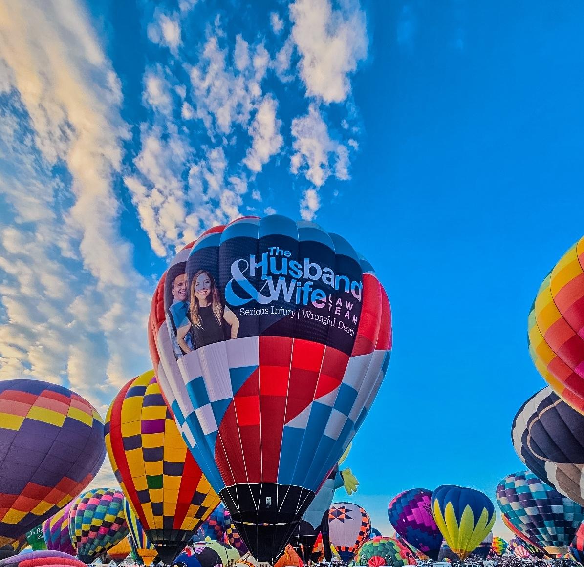 The Husband & Wife Law Team balloon soars above the Albuquerque International Balloon Fiesta, adding its colors to New Mexico’s iconic morning sky.
