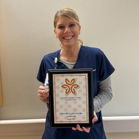 Nurse Jamie smiles while holding her Guardian Angel plaque and pin