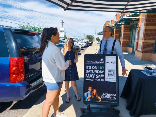 Mark and Alexis Breyer talk with a woman beside a table with giveaway items