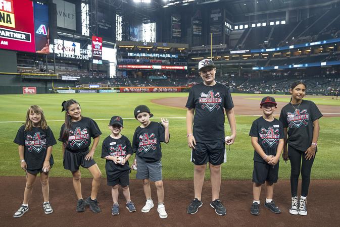 A group of Husband & Wife Law Team Kids Take the Field contest winners gathers on Chase Field, celebrating a memorable experience at the home of the Arizona Diamondbacks.