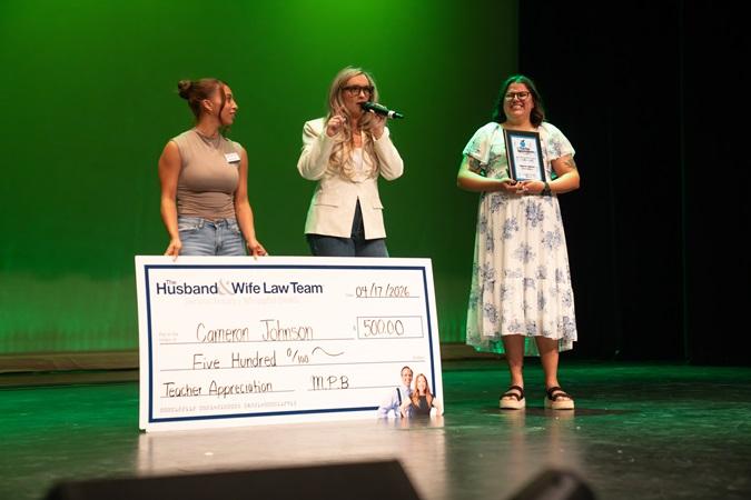 Hannah and Jen from the Husband and Wife Law Team present Ms. Johnson with a giant $500 check.