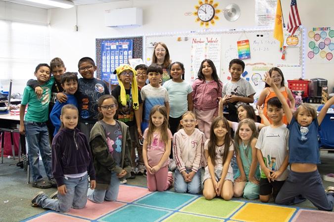 Ms. Noble and Zuni students pose together in a colorful classroom.