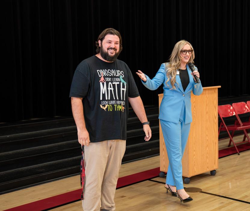 Mr. Knowles joins Jen from the Husband & Wife Law Team on stage as students and staff celebrate his Teacher of the Month recognition at Val Vista Academy.